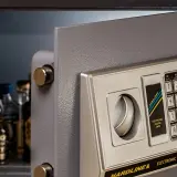 Coffre-fort ouvert avec des bouteilles à l'intérieur. Si vous vous demandez comment ouvrir un coffre de voiture bloqué, ce coffre-fort électronique pourrait vous donner des idées.