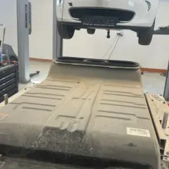 Un mécanicien travaille sur une batterie de voiture électrique, peut-être pour un changement de batterie chez Renault.