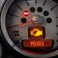 Voyant moteur allumé sur un tableau de bord, indiquant un problème P0303. Le voyant "BRAKE" est aussi allumé.