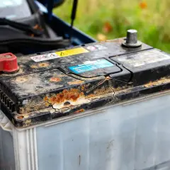 Batterie de voiture rouillée et fissurée, signe d'une durée de vie batterie voiture réduite.