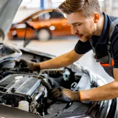 Mécanicien travaillant sur le moteur d'une voiture. Il explique comment changer une batterie de voiture sans perdre les données.