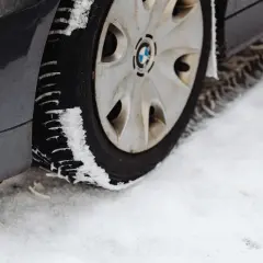 Pneu de voiture sur la neige. La neige s'accumule sur le pneu, illustrant pourquoi les pneus 4 saisons sont à éviter en conditions hivernales extrêmes.