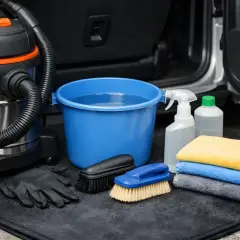 Kit pour nettoyer moquette voiture : aspirateur, seau d'eau, brosses, gants, spray et serviettes microfibres.