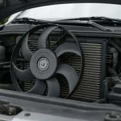 Le ventilateur de voiture est visible devant le radiateur, prêt à refroidir le moteur froid.