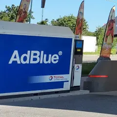 Station-service Total avec une pompe AdBlue à la vue. Des drapeaux aux couleurs nationales flottent au-dessus.