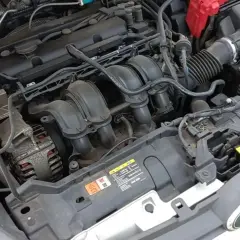 Moteur de Ford Fiesta essence. Le démarreur est caché sous le collecteur d'admission, près de l'alternateur.