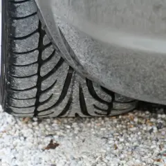 Gros plan sur un pneu m+s usé, posé sur un chemin de gravier. La bande de roulement est bien visible, prête pour affronter toutes les conditions.