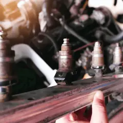 Un mécanicien examine un injecteur qui claque, rouillé et usé, prêt à être remplacé dans le moteur d'une voiture.