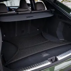 Coffre d'Audi Q5 vert, avec filet de rangement. L'emplacement de la batterie est discret sous le plancher.