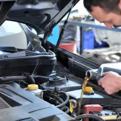 Mécanicien versant de l'huile moteur dans une Clio 2. Le prix de la vidange est abordable pour maintenir votre véhicule en bon état.