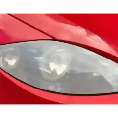 Phare de voiture rouge terni, prêt pour un nettoyage efficace avec du vinaigre blanc.