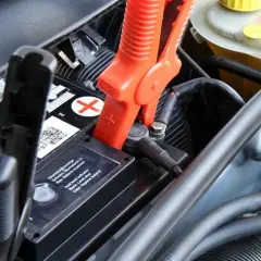 Pinces rouges connectées à la batterie pour recharger batterie voiture. Le niveau d'acide est indiqué.