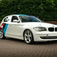 BMW blanc avec bandes tricolores sur le flanc, prêt pour son entretien.