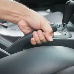 Main d'un conducteur actionnant le frein à main bloqué dans une voiture.