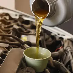 Huile neuve versée dans un entonnoir pour la vidange d'une Polo 6. Le moteur est visible en arrière-plan.