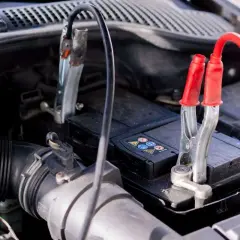 Pinces de démarrage connectées à une batterie de voiture, signe d'une conséquence batterie faible voiture.