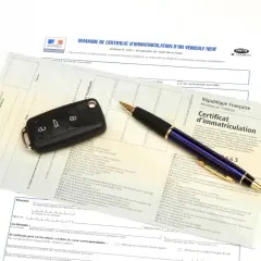 Carte grise, clé de voiture et stylo sur un document officiel.