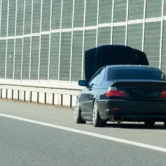 Panne sur l'autoroute. Capot ouvert, portière conducteur ouverte, triangle de signalisation rouge. Un entretien véhicule s'impose.