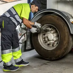 Un mécanicien en tenue de travail effectue le couple serrage roue voiture d'un camion avec une clé à chocs.