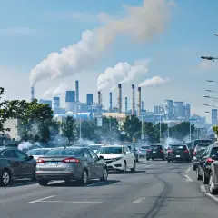 Trafic dense sous un ciel pollué par les cheminées d'une usine, un contrôle impossible des émissions à l'échappement.