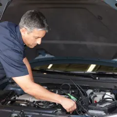 Mécanicien diagnostiquant un problème de démarrage à chaud sur un moteur de voiture avec un appareil électronique.