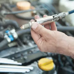 Main d'un mécanicien tenant une bougie d'allumage, prête à être installée dans le moteur d'une voiture.