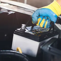 Main tenant une batterie de voiture, prêt à la changer.