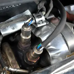 Sonde lambda défectueuse : câblage visible, connecteurs et partie métallique rouillée. Un symptôme de problème moteur.