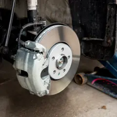 Freinage spongieux, un symptôme d'air dans le circuit de freinage. Le cric bleu soutient la voiture près du disque de frein.