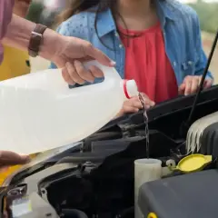 Main d'homme versant du liquide dans le réservoir, vérifiant le niveau liquide de frein.