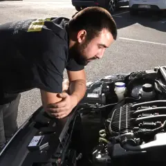Un mécanicien examine un moteur de voiture, soucieux du risque de casse moteur.