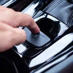 Main d'une personne appuyant sur le bouton du frein à main automatique. Voici comment débloquer un frein à main automatique.