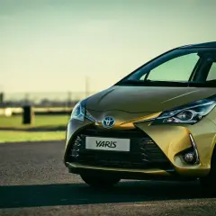 Toyota Yaris hybride dorée sur route asphaltée, prête pour sa vidange.