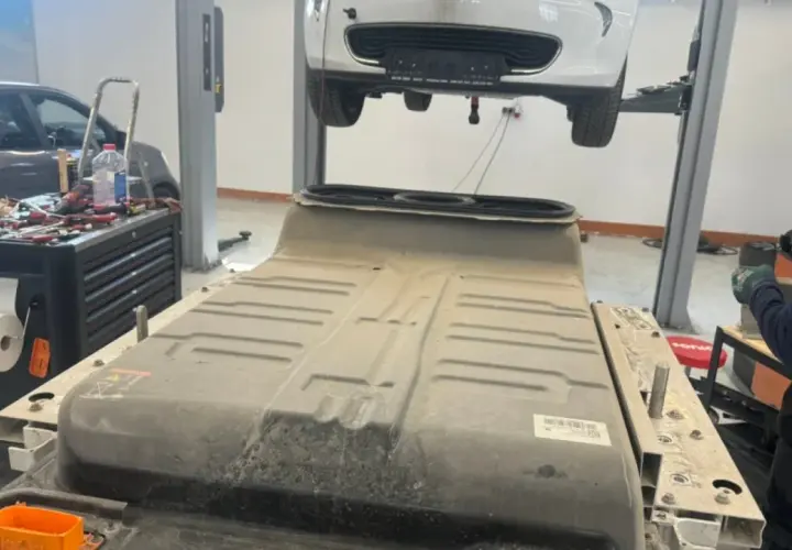 Un mécanicien travaille sur une batterie de voiture électrique, peut-être pour un changement de batterie chez Renault.