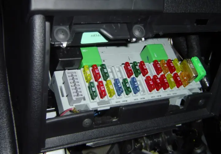 Boîte de fusibles de voiture avec des fusibles colorés de différentes ampérages. Un fusible de 20A est visible.