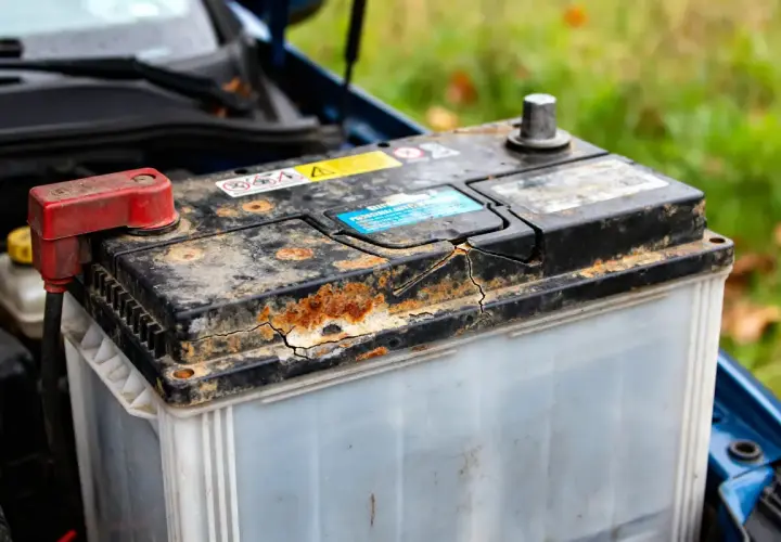 Batterie de voiture rouillée et fissurée, signe d'une durée de vie batterie voiture réduite.