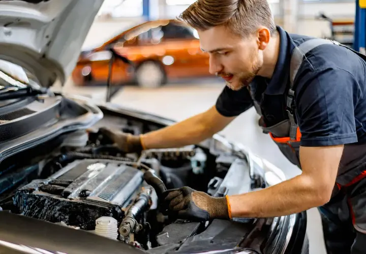 Mécanicien travaillant sur le moteur d'une voiture. Il explique comment changer une batterie de voiture sans perdre les données.