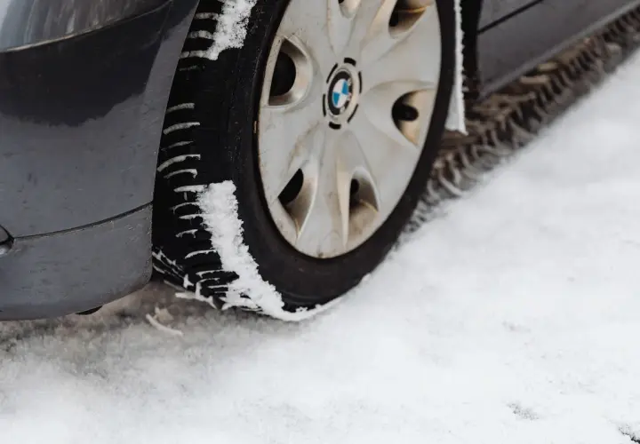 Pneu de voiture sur la neige. La neige s'accumule sur le pneu, illustrant pourquoi les pneus 4 saisons sont à éviter en conditions hivernales extrêmes.