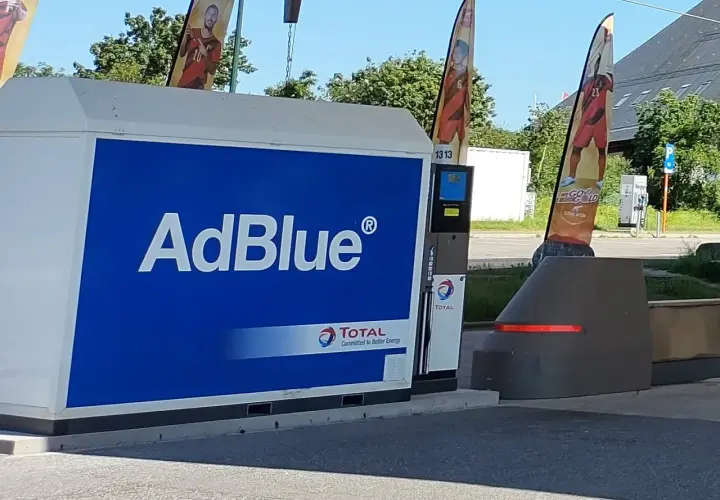 Station-service Total avec une pompe AdBlue à la vue. Des drapeaux aux couleurs nationales flottent au-dessus.