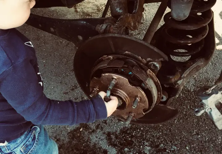 Un enfant touche le système de freinage d'une voiture. Un diagnostic freinage gratuit est peut-être en cours.