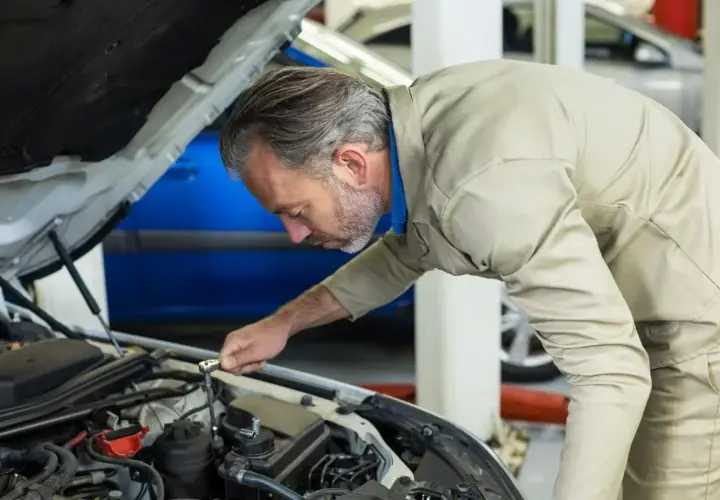 Mécanicien concentré sur le moteur, s'assurant de la pleine puissance moteur de la voiture.