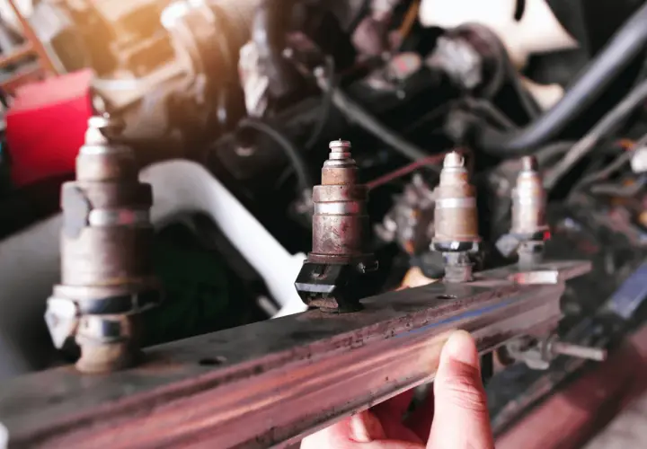 Un mécanicien examine un injecteur qui claque, rouillé et usé, prêt à être remplacé dans le moteur d'une voiture.