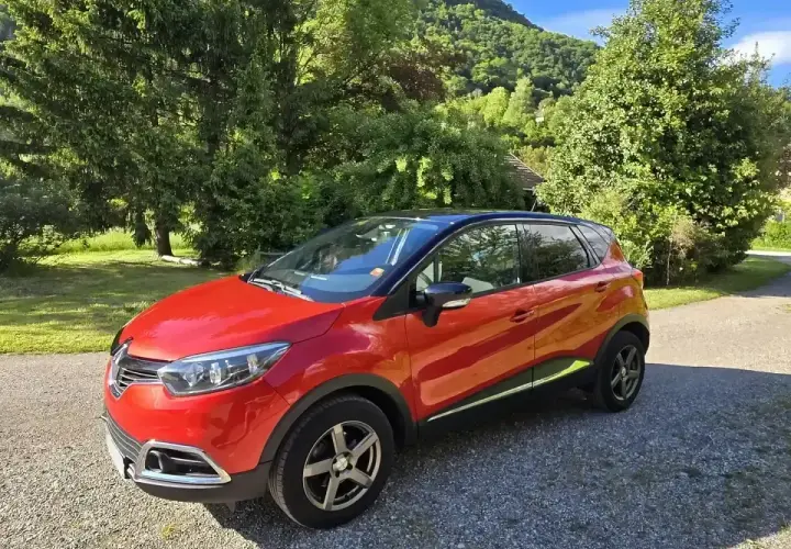Renault Captur rouge garé dans un paysage verdoyant. Idéal pour connaître le prix révision Renault Captur 60000 km.