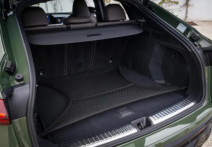 Coffre d'Audi Q5 vert, avec filet de rangement. L'emplacement de la batterie est discret sous le plancher.