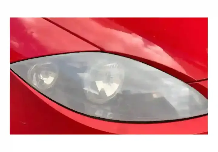 Phare de voiture rouge terni, prêt pour un nettoyage efficace avec du vinaigre blanc.