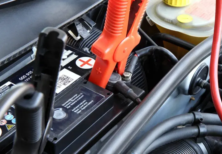 Pinces rouges connectées à la batterie pour recharger batterie voiture. Le niveau d'acide est indiqué.