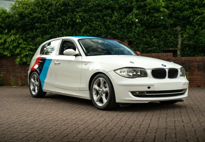 BMW blanc avec bandes tricolores sur le flanc, prêt pour son entretien.