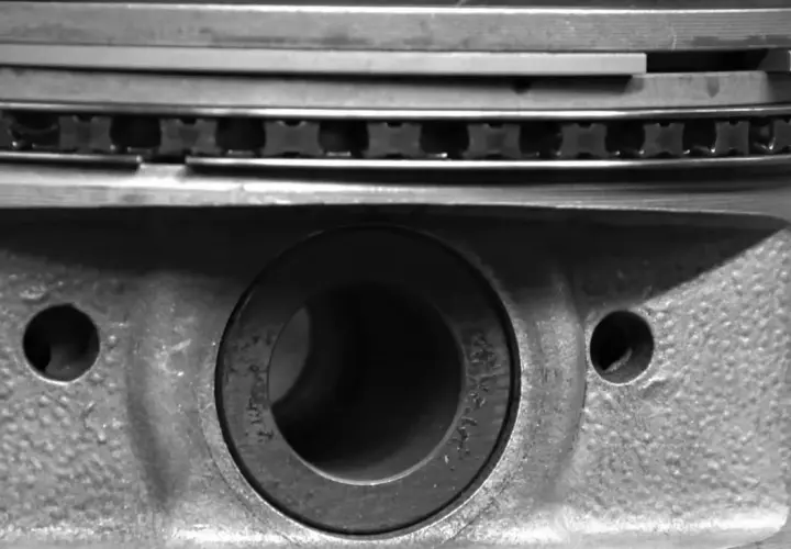 Gros plan sur un piston de moteur, montrant les segments et le logement de l'axe. La segmentation moteur est essentielle pour l'étanchéité.