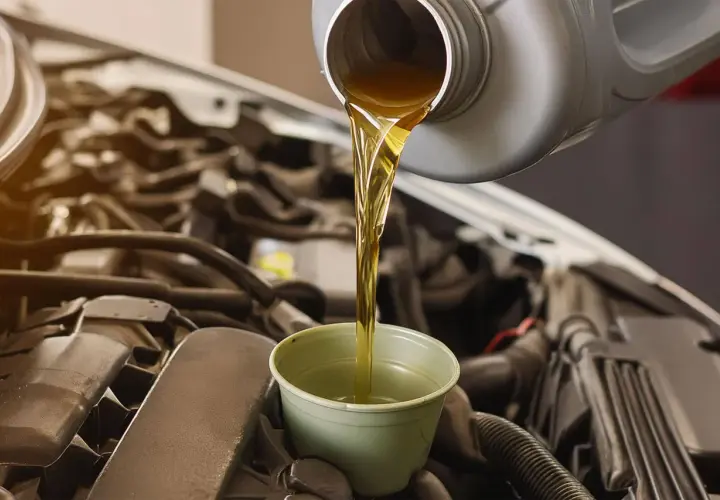 Huile neuve versée dans un entonnoir pour la vidange d'une Polo 6. Le moteur est visible en arrière-plan.