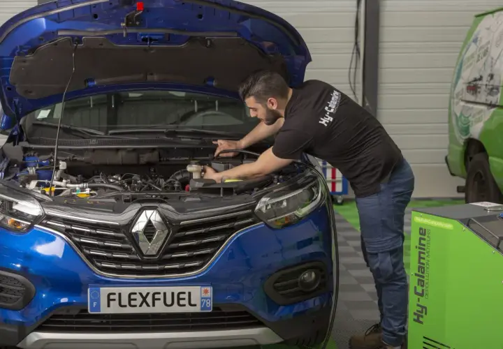 Mécanicien effectuant un décalaminage moteur essence. Avis positifs sur cette méthode de dépollution.
